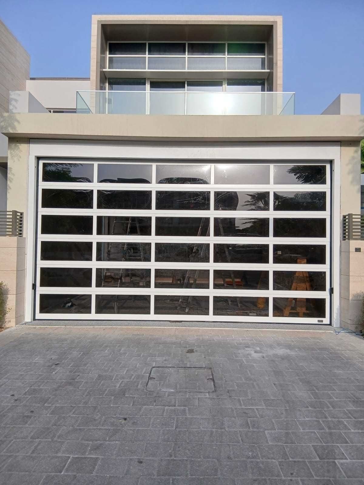 Full-glass vision garage door with white aluminium frames on a contemporary villa