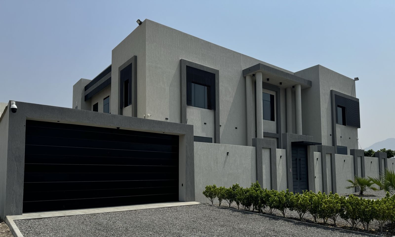 Black flush-panel sectional garage door on a modern grey villa — BAB ALSARAY installation