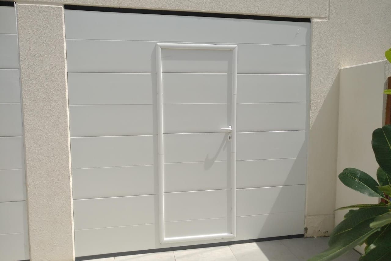 White sectional garage door with a built-in pedestrian wicket door and handle
