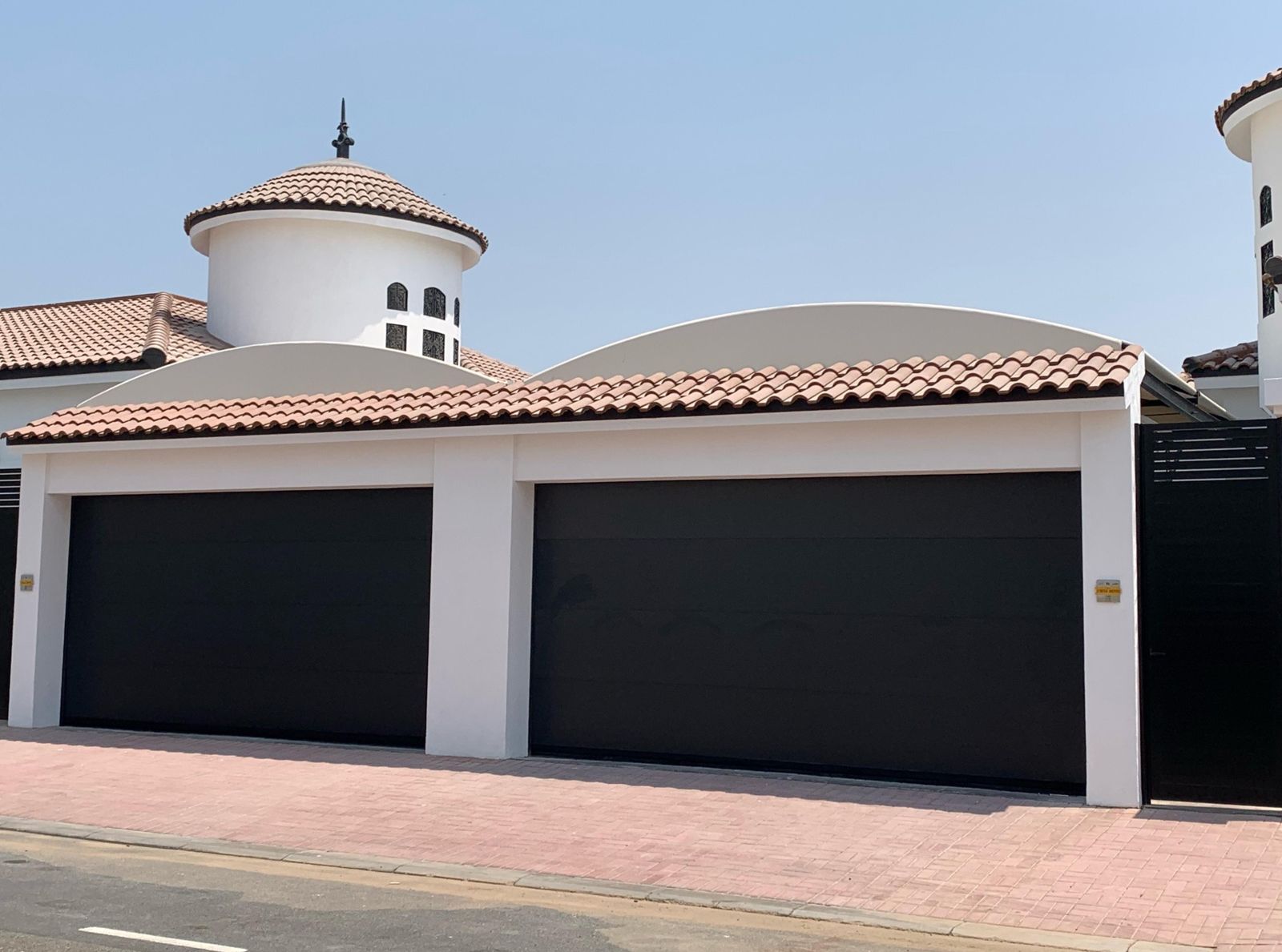 Two black sectional garage doors on a Mediterranean-style villa in the UAE — a BAB ALSARAY installation