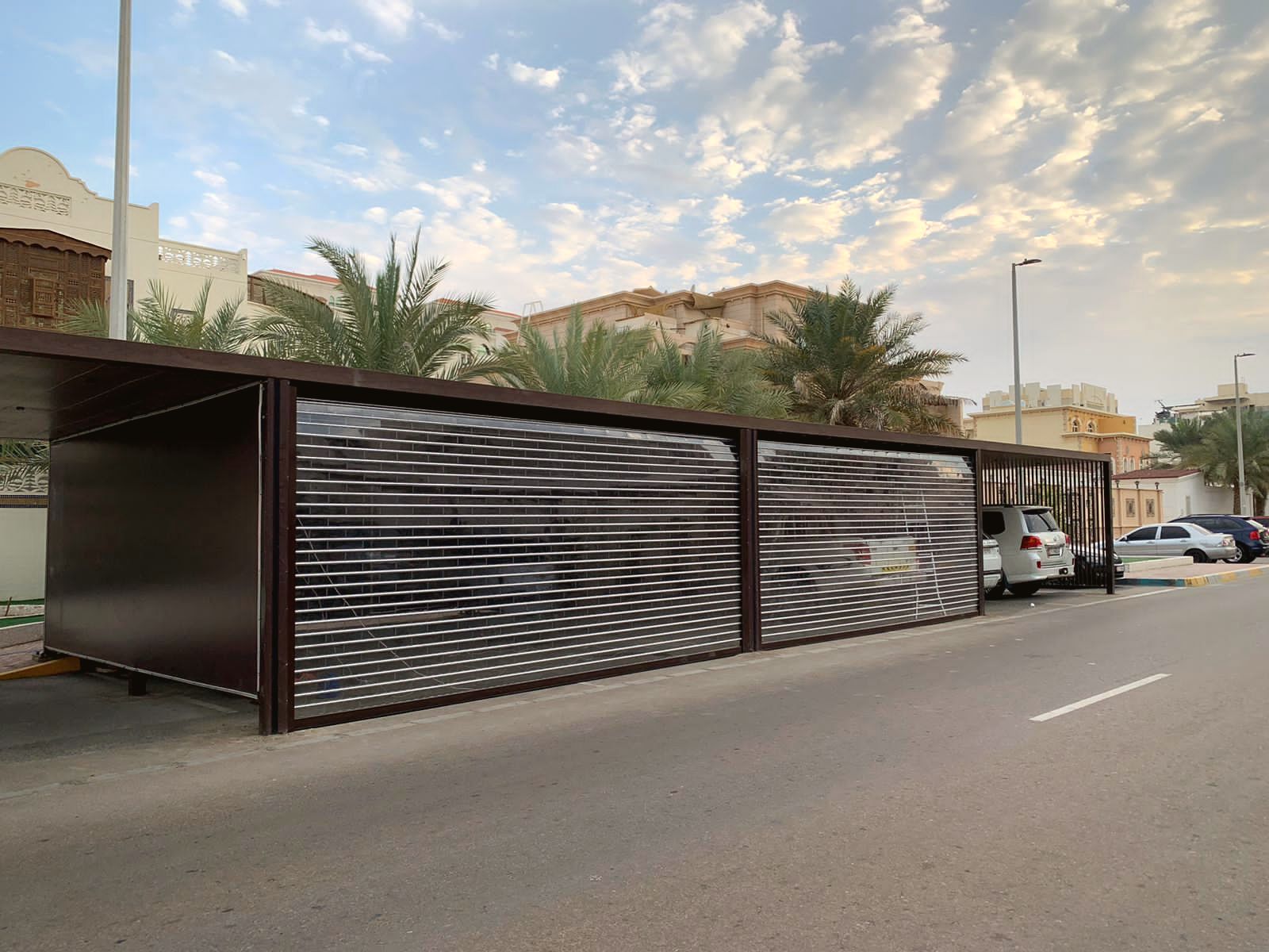 Clear polycarbonate rolling shutters closing a long villa carport in the UAE — BAB ALSARAY installation